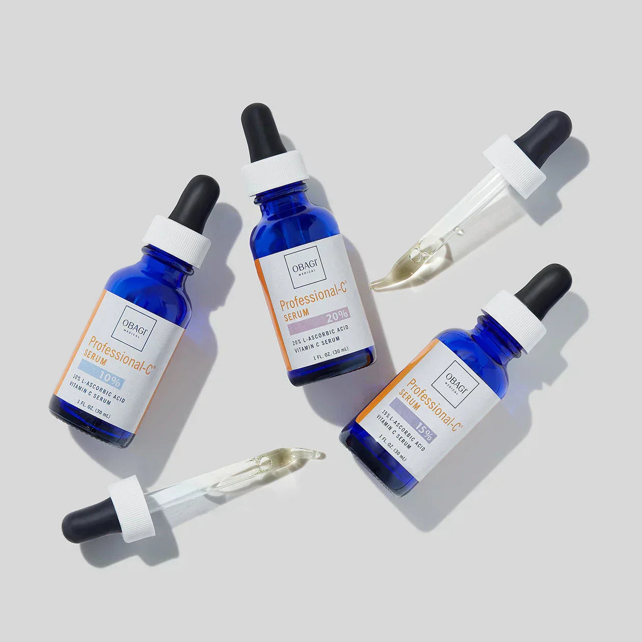 Three blue serum bottles with droppers on a light gray background
