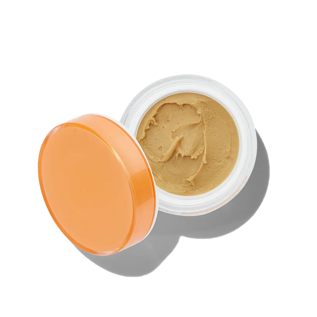 Open jar of beige cream with an orange lid on a white background